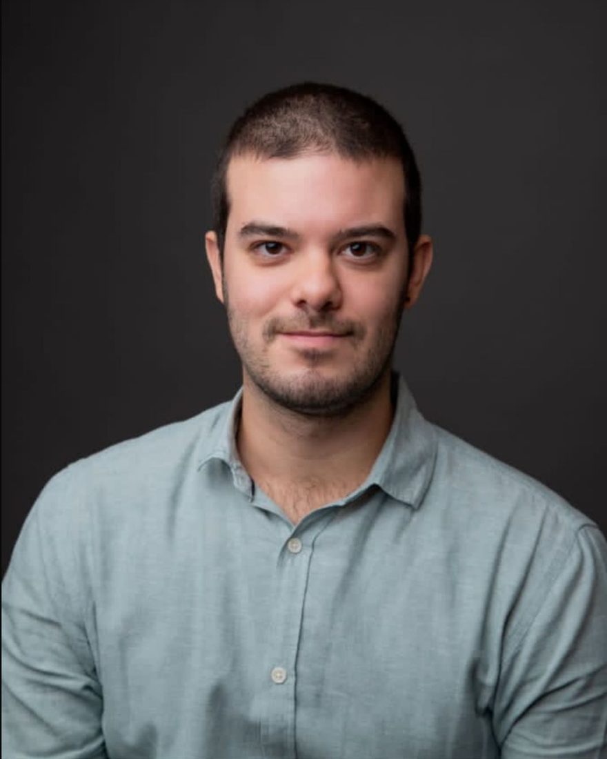 Leonardo Santa Cecília, psicólogo, sorrindo, de camisa azul-clara